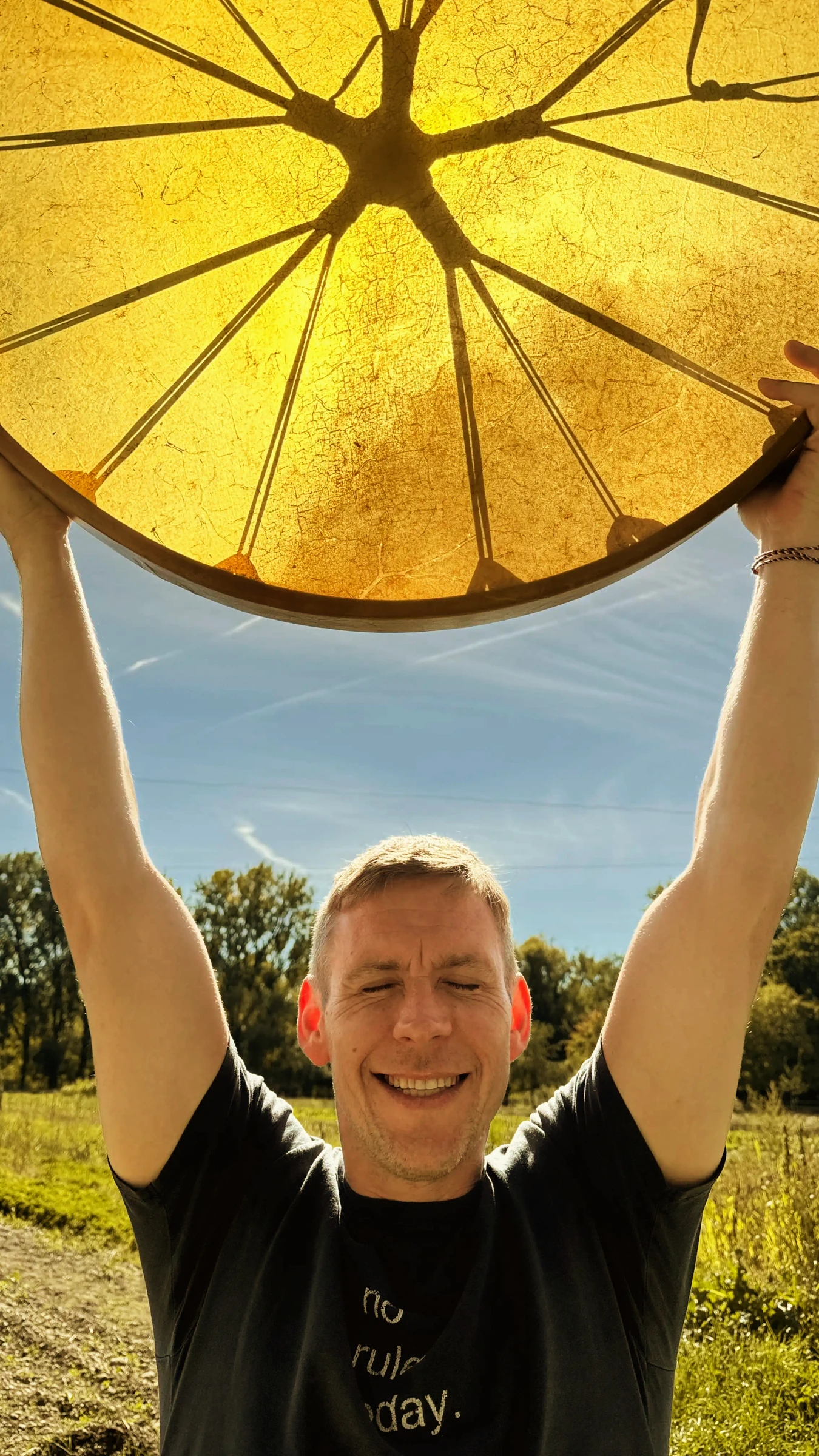 Teilnehmer hält seine frisch gebaute Trommel am Amperhof ins Sonnenlicht